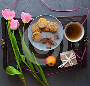 Mother`s Day, woman`s day. tulips ,presents ,tea and sweets on wooden background