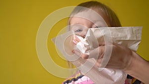 Mother`s hand helping little girl to blow nose by napkin