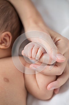 Mother`s hand holding infant baby boy`s hand with care.