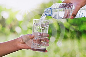 mother& x27;s hand pouring drinking water into glass form bottle give