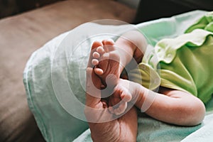 Mother`s hand touching tiny feet of newborn baby. Togetherness, new life.