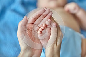 Mother`s hands carefully holding baby`s feet, selective focus