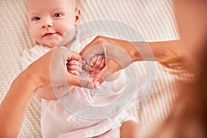 Mother`s hands holding baby`s hands. folded symbol of heart and love from fingers. motherhood and care for the baby