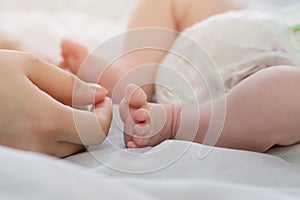 Mother`s hands near the little feet of her newborn baby. Mom and Child. A beautiful conceptual image of motherhood
