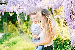 Mother s kissing her son on the cheek under a wysteria tree