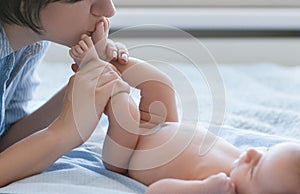 Mother`s love tenderness feet kiss newborn baby