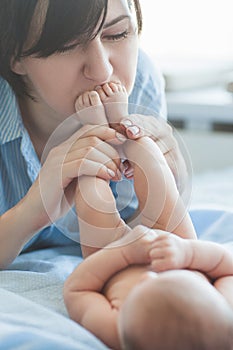 Mother`s love tenderness feet kiss newborn baby