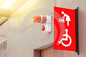 Mother`s room and disabled toilet sign on red tab with red siren light above the door of public toilet