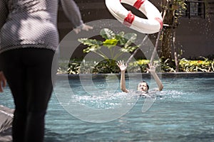 Mother is saving the life of a teenager daughter using ringbuoy to rescue drowning in dangerous situation; asian child girl