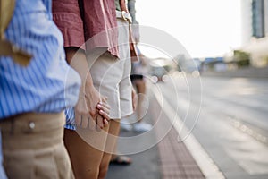 Mother and school girl with a backpack holding hands while crossing a busy road.