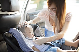 Mother securing baby in the car seat