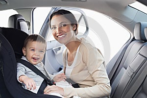 Mother securing her baby in the car seat photo