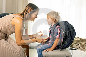 Mother, sending her firstgrader boy to school, first day at school, giving him books and a box with snack