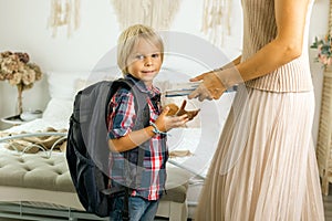 Mother, sending her firstgrader boy to school, first day at school, giving him books and a box with snack