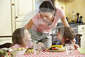 Mother Serving Meal To Children In Kitchen