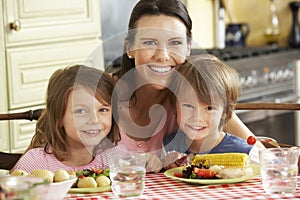 Mother Serving Meal To Children In Kitchen