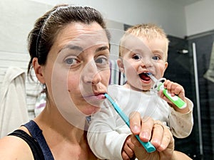 Mother and toddler brushing their teeth together photo