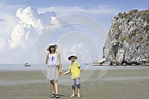 Mother shakes hands with son walking on the beach. background boat and sea at Phraya Nakhon Cave National Park , Prachuap Khiri