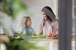 Mother share family recipes teaches daughter preparing vegetable salad