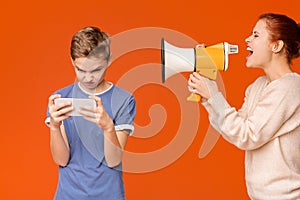 Mother shouting through megaphone at boy with joystick