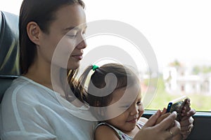 Mother showing her child educational videos on a cell phone, while traveling on a train/bus