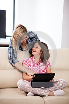 Mother showing her cute teenage daughter something on the tablet PC