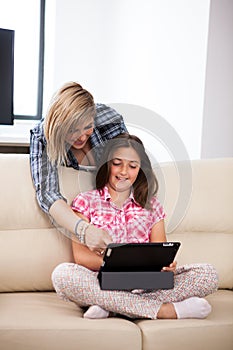 Mother showing her cute teenage daughter something on the tablet PC