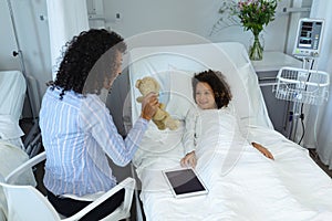 Mother showing her son teddy bear in the ward at hospital