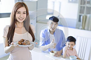 Mother showing tasty food and father showing thumbs up. Happy Asian  family having dinner at home