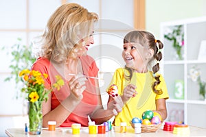 Mother showing to her child how to paint Easter