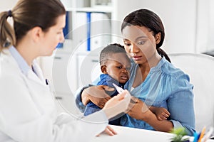 Mother with sick baby son and doctor at clinic