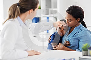 Mother with sick baby son and doctor at clinic