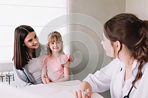 Mother or sister with small girl visiting family doctor in the clinic