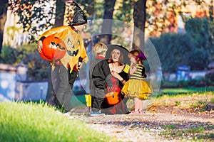 Mother sit speaking with boys and girl wear Halloween costumes