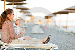 Mother sitting with baby on sunbed on the beach