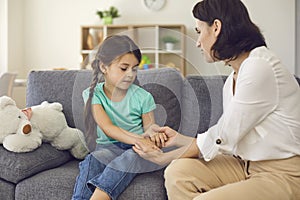 Mother sitting with daughter, holding her hands, talking to her and teaching her something photo