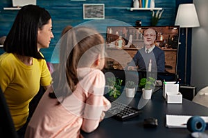 Mother sitting beside daughter talking with remote senior retired man