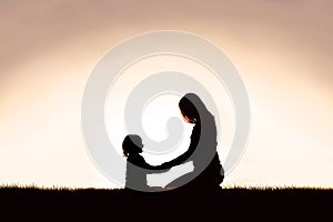 Mother Sitting Holding Hands with Young Child Outside at Sunset