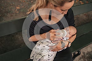 Mother sitting outside feeding her baby boy with a bottle