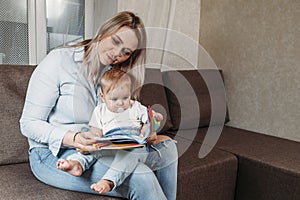 Mother sitting with son reading story indoors sitting on the couch