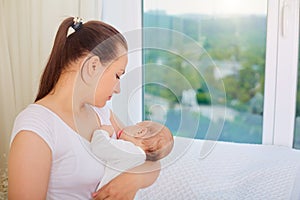 Mother with a sleeping baby in her arms at the window.