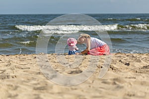 Mother with small baby girl relaxing on sea beach