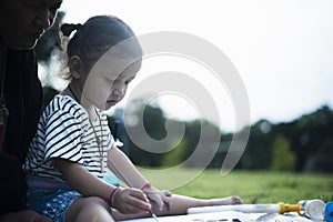 Mother with small child painting in the garden on the lawn Mother and daughter drawing pictures of nature