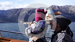 Mother and a small child are sailing on a boat past the island of Gospa od Skrpjela. Montenegro