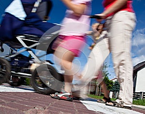 Mother with small children and a pram crossing a street