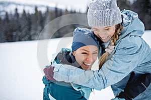 Mother with small daughter having fun outdoors in winter nature.