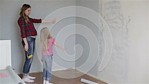 A mother and a small daughter satisfied with their wallpapering.