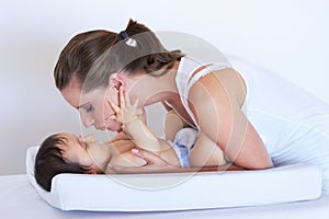 Mother, smile and baby kiss at home on diaper changing table with happiness. Family, house and young child with mom