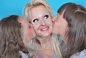 A mother smiles as she receives a kiss on the cheek