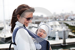 Mother and a smiling cute baby boy in a baby carrier